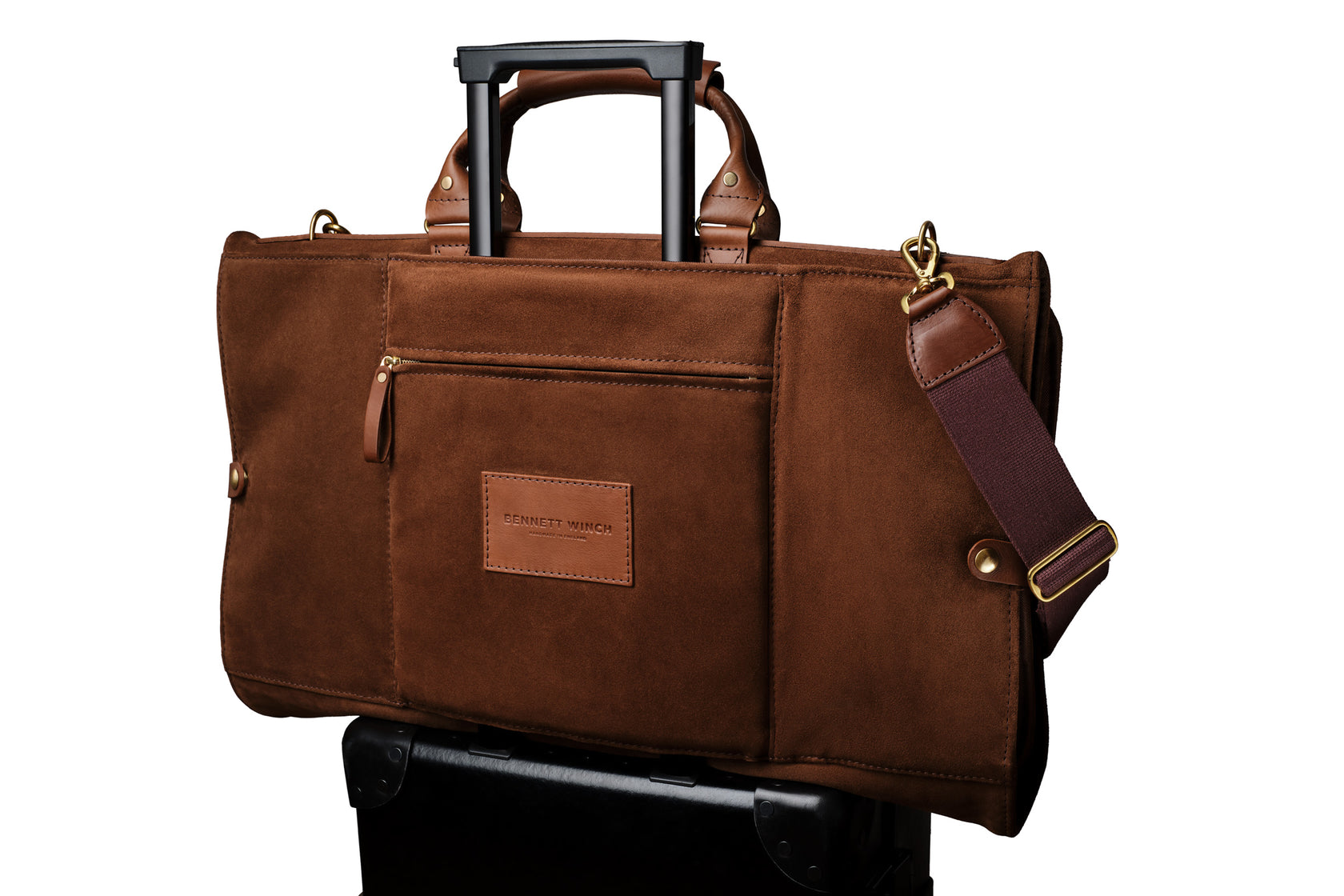 high end brown suede trifold on top of a suitcase