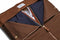 a view of the inside of the brown suede trifold half zipped with clothes inside
