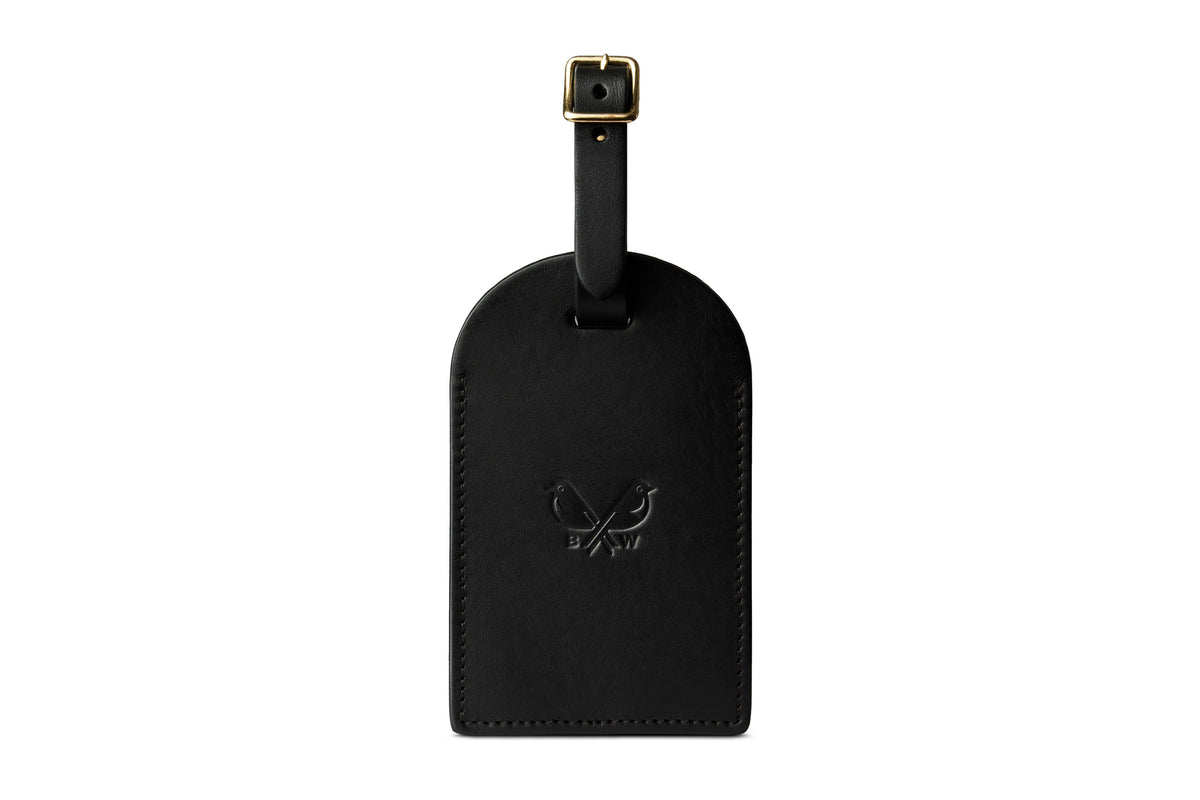 Front of a black leather luggage tag with the Bennett Winch logo and leather strap with brass buckle.