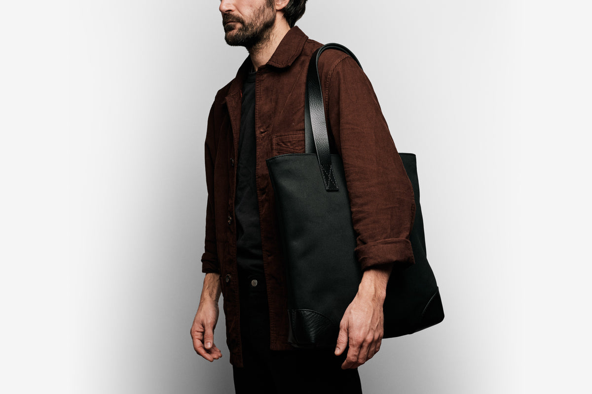 man wearing the black canvas tote on his shoulder