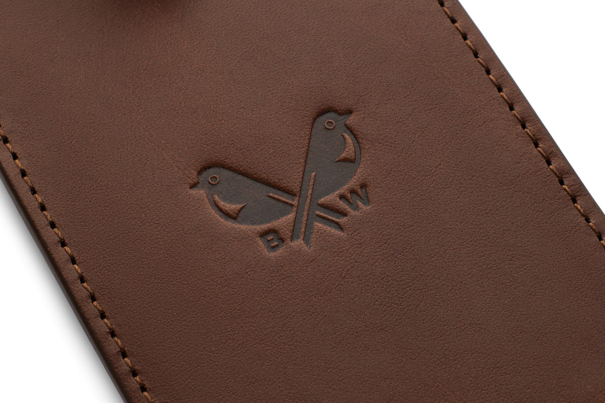 Close-up of the Bennett Winch logo embossed on a brown Italian leather luggage tag.