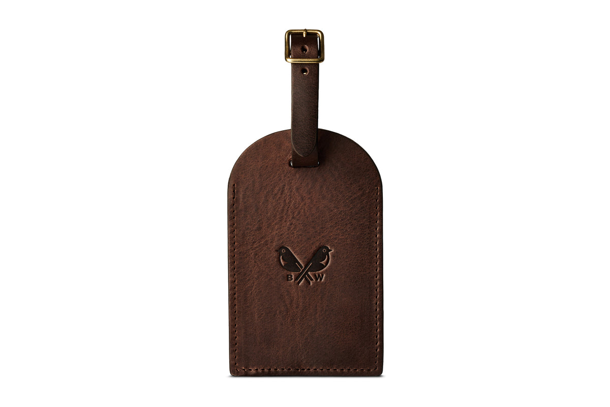 Front of a dark brown leather luggage tag with Bennett Winch logo and leather strap with brass buckle.