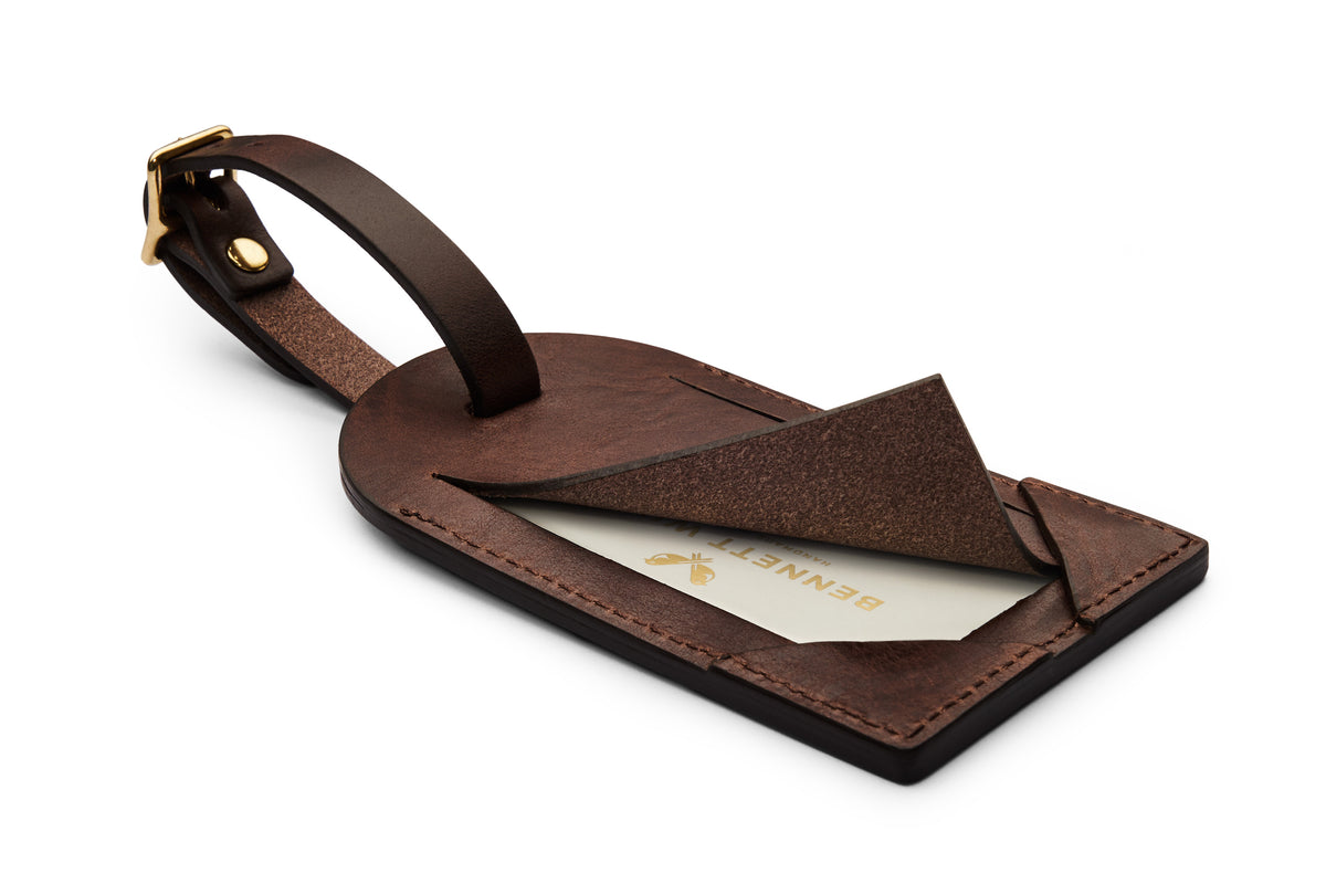 Back of dark brown leather luggage tag with flap open, showing concealed business card.