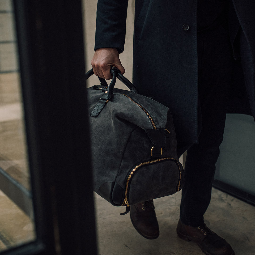 man holding the suede weekender bag lifestyle