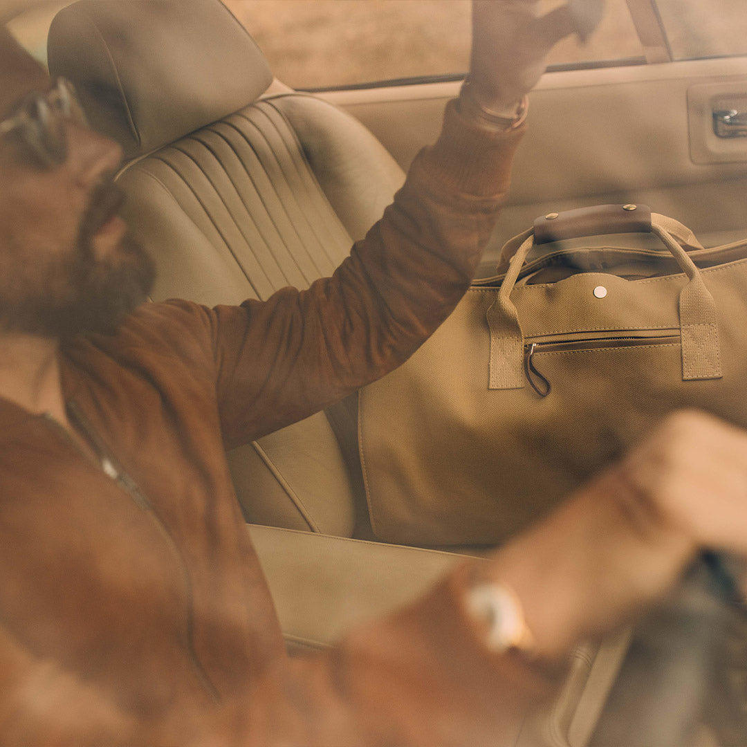 man driving on a trip with the suit carrier holdall bag from Bennett Winch lifestyle