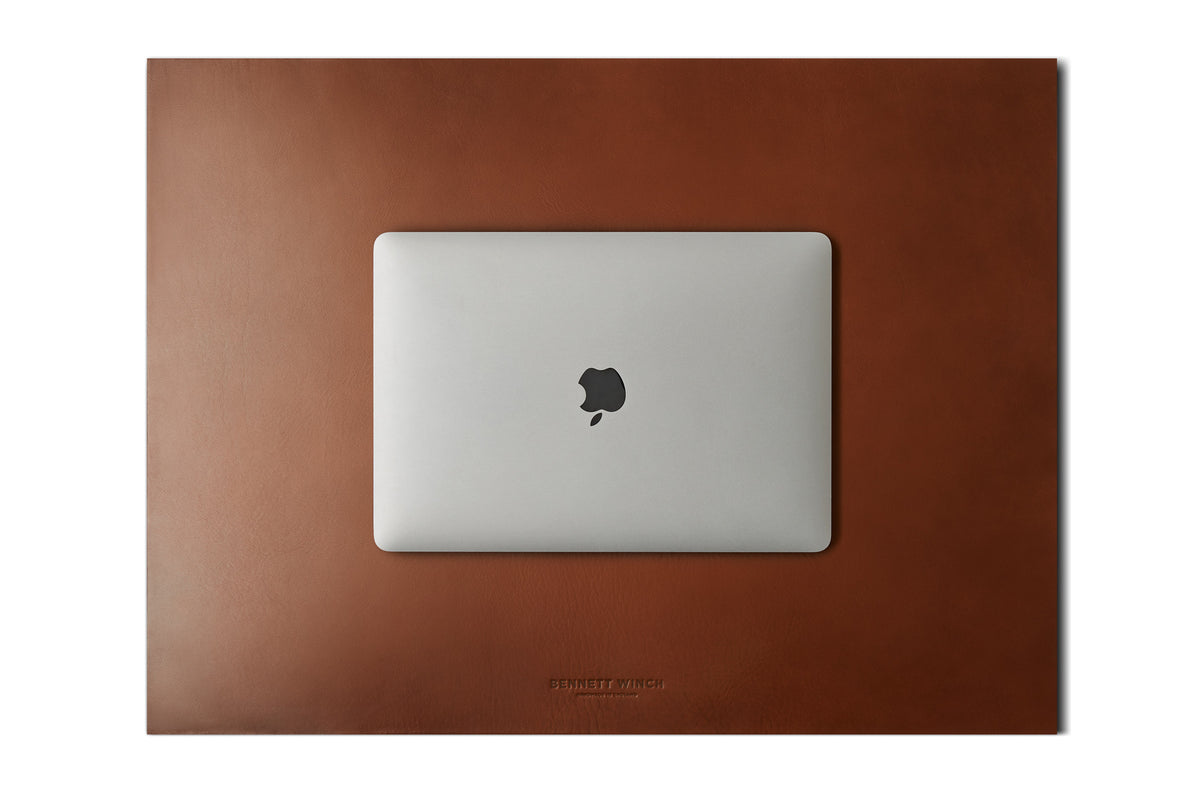 top shot of the Italian veg tanned light brown leather desk blotter and a closed laptop on top