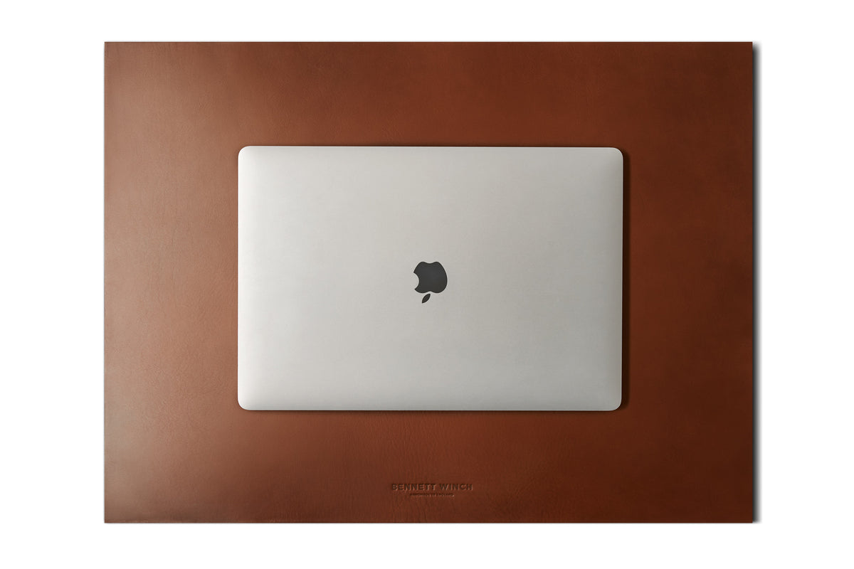 Italian veg tanned light brown leather desk blotter with a closed laptop on top