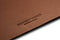 A close up of the Bennett Winch logo embossed on the brown leather desk mat