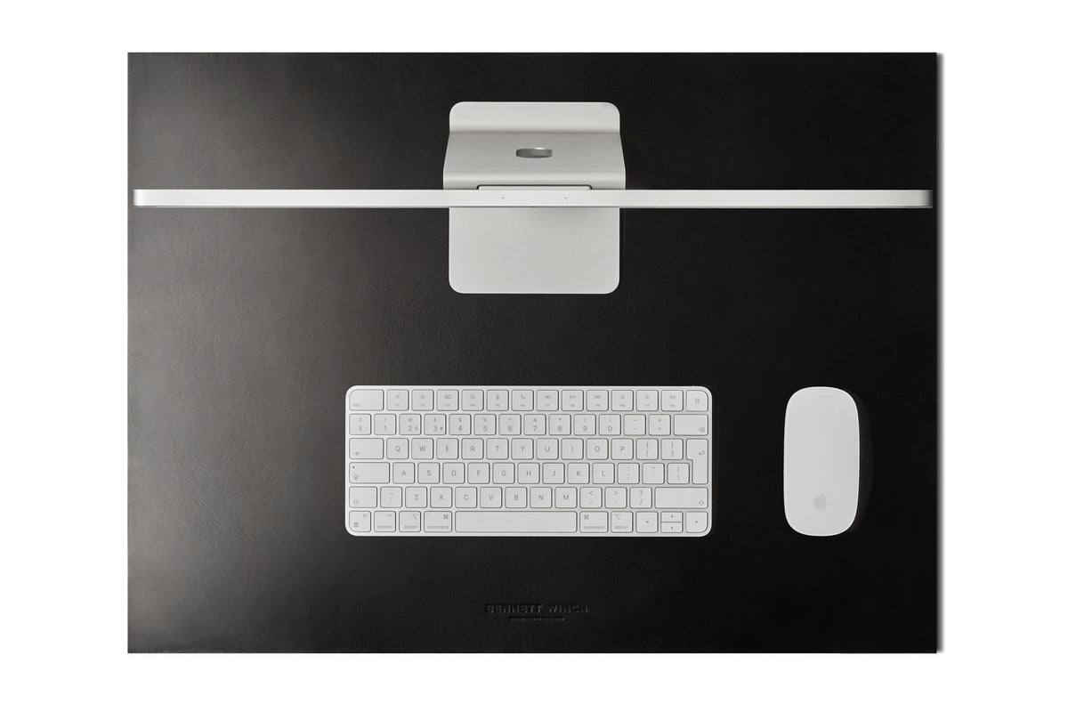 Italian veg tanned black leather desk blotter with a closed laptop on top